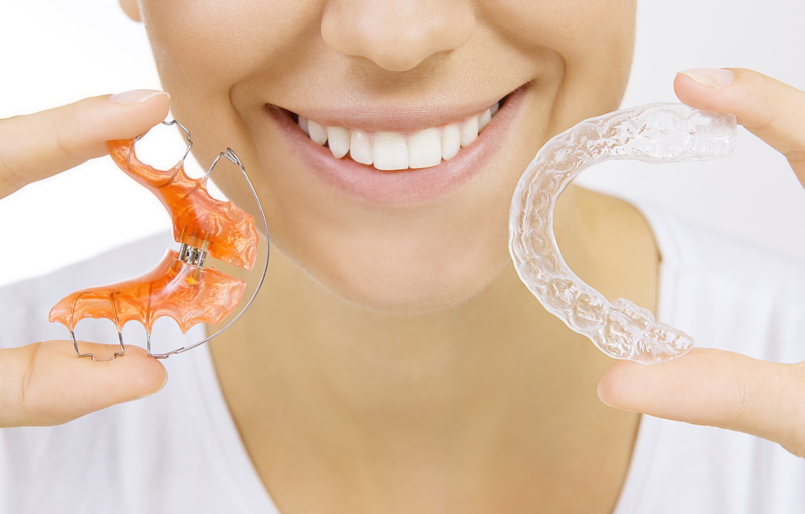 Beautiful smiling girl holding Hawley and Essix retainer